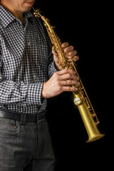 Naklejka premium soprano saxophone in hands on a black background