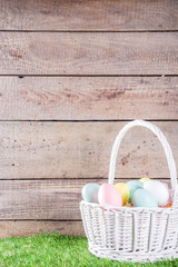 Colorful pastel Easter eggs on green and wooden garden terrace.  Funny spring decoration. Happy Easter greeting card background.