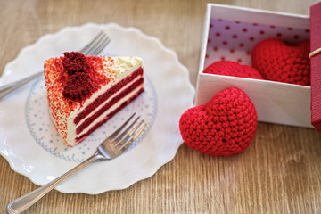 Heart shaped yarn on the table near gift box and Red Velvet strawberry cheese cake.