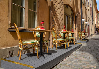 Fototapeta na wymiar Wicker chairs and round tables with gas lamps on the terrace near the street cafe