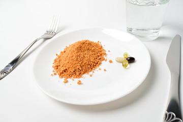 Tomato protein soup powder and multivitamins on a plate. Meal replacement. Dry soup. Multivitamins, astaxanthin, fish oil, omega pills.