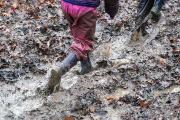 Young children playing in a muddy puddle