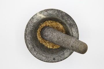 Top view close up on isolated gray basalt stone mortar with with pestle and spices, white blank...