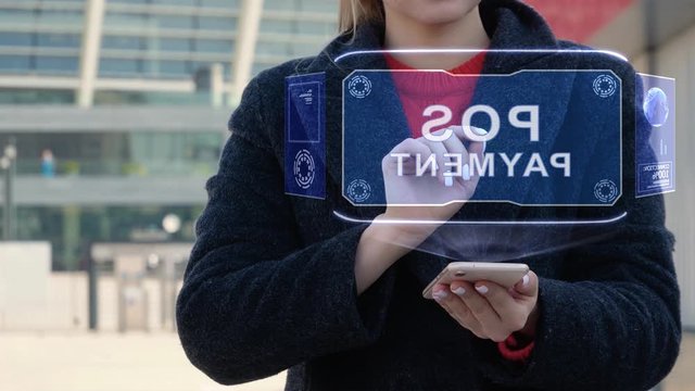 Unrecognizable woman interacts HUD hologram with text POS Payment. Girl in the coat uses the technology of the future mobile screen on the background of the city