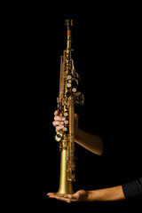 soprano saxophone in hands on a black background