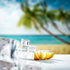 Desk of ice cubes and blurred background of palms with sea 