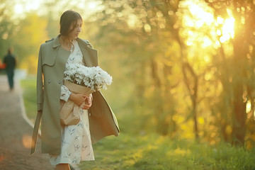girl waiting for a city date / happy girl with a bouquet of flowers walking in the urban landscape, soft light