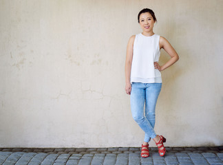 Smiling Asian women wearing jeans and a blouse standing outside