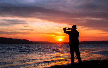silhouette of a happy unrecognizable man in love at sunset on the lake