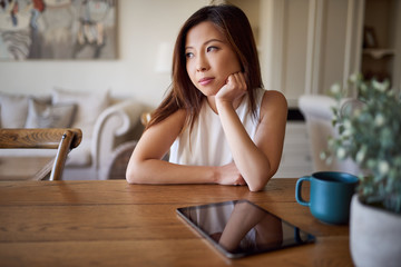 Young Asian woman sitting at home deep in thought