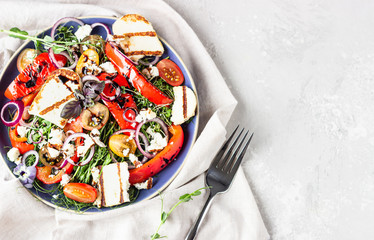 Grilled haloumi (halloumi) cheese salad witch tomato, baked pepper, micro green and onion on a blue plate. Keto diet, healthy food.