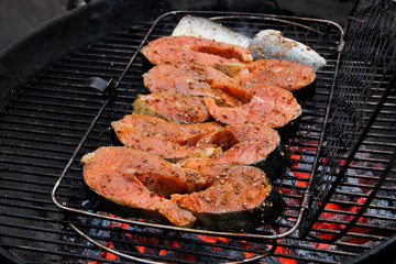 Salmon filet on a barbeque grid. Redfish steaks in the marinade over hot coals. Close-up of a grilled salmon steaks.