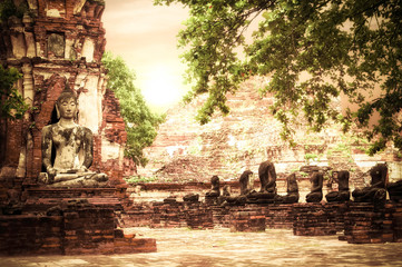 Buddha at Wat Mahathat ruins under sunset sky. Ayutthaya, Thailand travel landscape and destinations