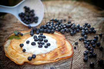 pancake with sour cream,is on the slice of wood ,blueberries around