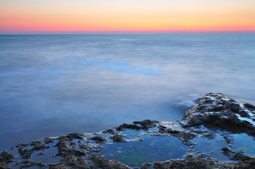 Beautiful sunset over wavy stormy Black sea rocky coastline in Crimea on summer day