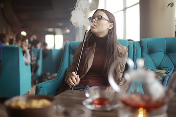 adult girl smokes a hookah in a cafe / modern interior, smoking, smoke, night club, day.