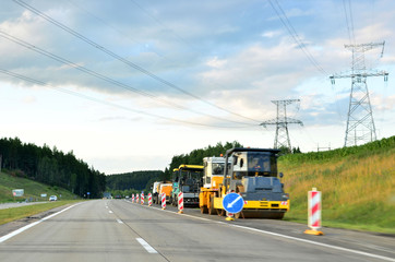 Naklejka premium Asphalt paver machine working at construction site during asphalt road repair. Paving roller machine on paving works.