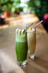 refreshing banana and spinach smoothie in a glass cup with a straw