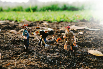 Miniature farmer is digging the soil to plant trees Taking care of preserving the environment and the world by planting trees, selective focus at miniature people               