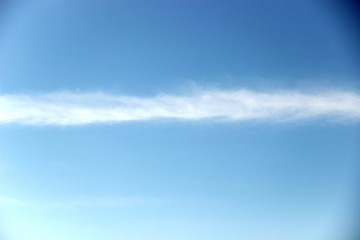 bright blue sky with a white wide strip of feather clouds. bright blue sky with a slight haze of feather clouds