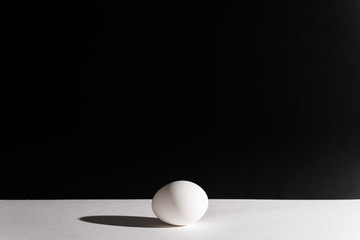 White egg on a black background in the center. Modern easter card. Design, visual art, minimalism
