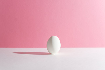 White egg on a pink background in the center. Modern easter card. Design, visual art, minimalism