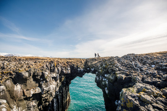 young wedding couple in black clothes stand on a rock near the atlantic ocean in Iceland