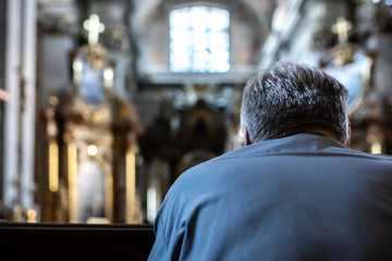 An unidentified man praying in a church.