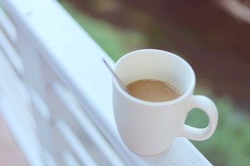 White coffee cup against blurred natural green background for drinks and beverage concept
