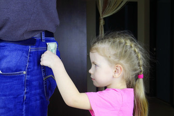A child steals money. A little girl steals money from the pocket of parents