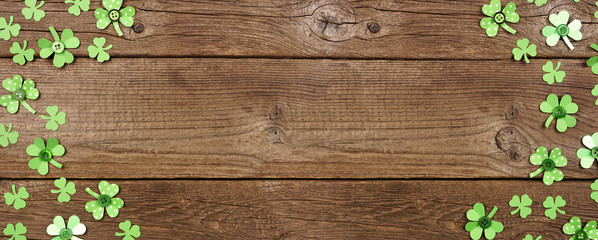 St Patricks Day banner with double border of handmade paper button shamrocks. Above view over a rustic wood background with copy space.