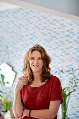 Mature woman smiling while standing in her stylish apartment