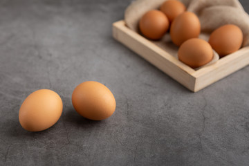 Chicken eggs on the wooden tray on the black cement floor. High angle view.