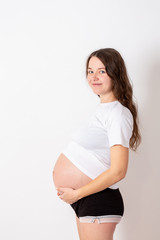 The young beautiful pregnant woman experiences strong emotions on a white background