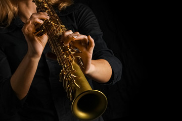 soprano saxophone in hands on a black background