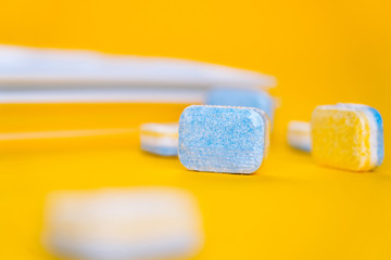 Cleaning dishwasher tablets on a yellow background. Group of bright colored soap tablet for washing...