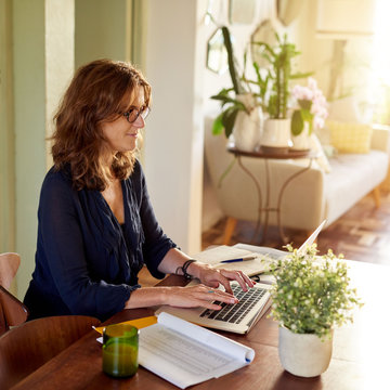 Smiling Mature Female Entrepreneur Working On A Laptop At Home