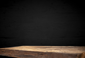 Empty wooden table on a dark concrete background, blurred brick wall, empty space for the product above.