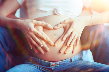 pregnancy concept childbirth and love / man and woman, big belly, hands in the shape of a heart,...