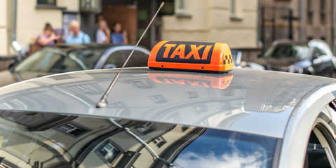 A taxi awaits passengers on a city street and reflects architecture