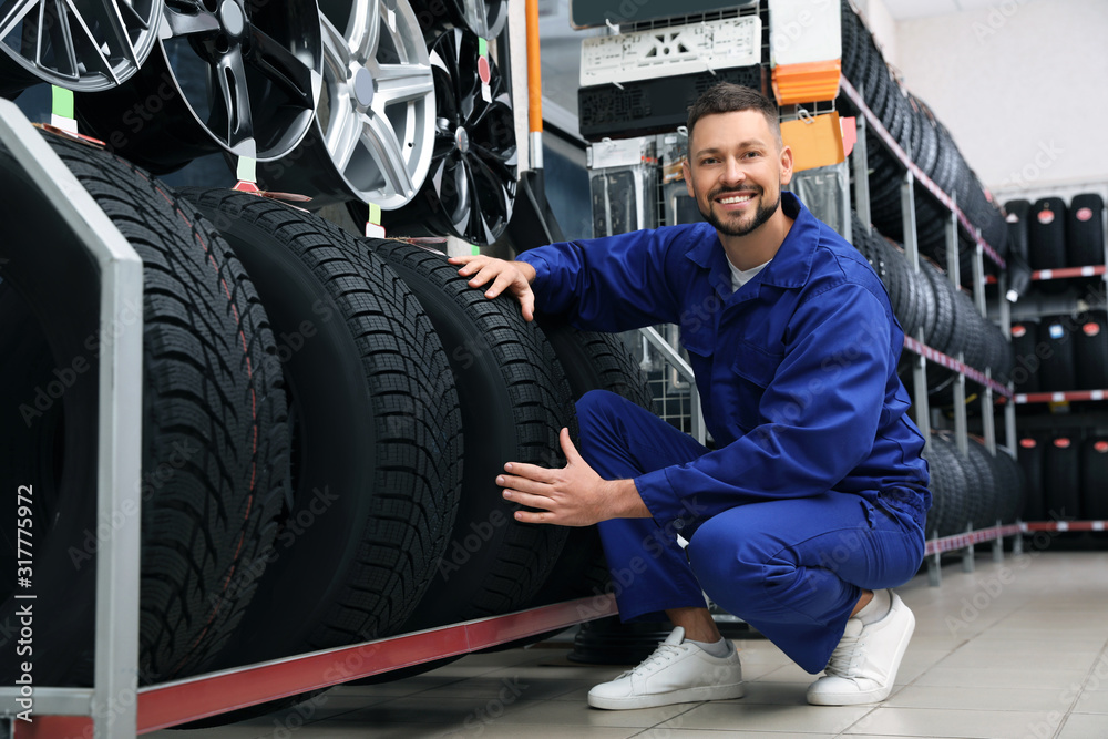 Canvas Prints Male mechanic with car tires in auto store