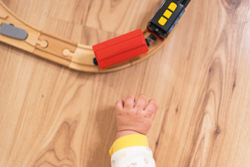 Baby is playing with small wooden train on the floor