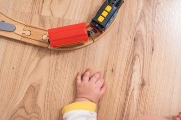 Baby is playing with small wooden train on the floor