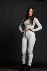 Fototapeta premium Young lady with hair in topknot standing with arms folded looking up. Capricious female model in grey dress biting lips thinking about her desire. Daydream concept
