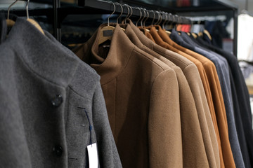 Clothes on a hanger autumn or winter coat at men's clothing store. Season time of sales and discounts.