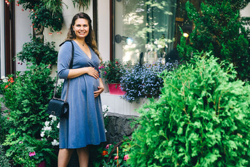 Funny beautiful pregnant blonde long-haired woman in blue dress sequin . Festive clothing for women awaiting a baby