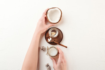 Obraz na płótnie Canvas Female hand using coconut oil cosmetics mockup. Skincare background. Woman holding cosmetics jar.
