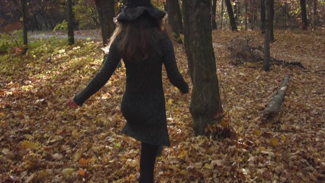 Young caucasian woman in halloween costume resting in the autumn forest. Recorded in Raw on Blackmagic camera.	