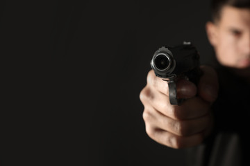 Professional killer on black background, focus on gun. Space for text