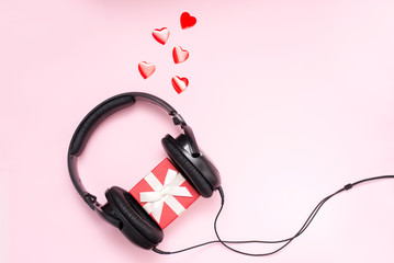 Love Music. Headphone with gift box and red hearts on pink background with copy space